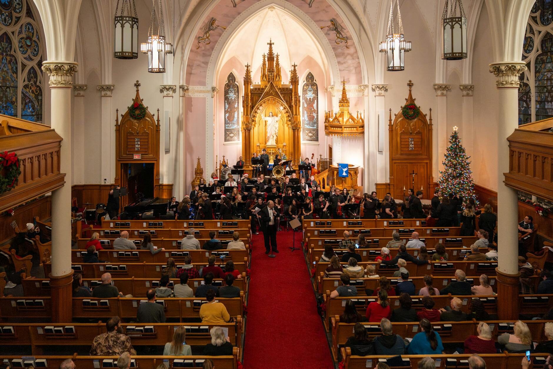 Christmas concert in a church interior with orchestra, audience, and Christmas tree