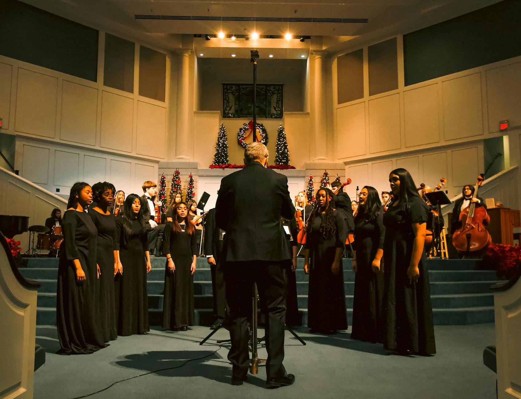 Conductor leading a mixed choir from behind, audience perspective