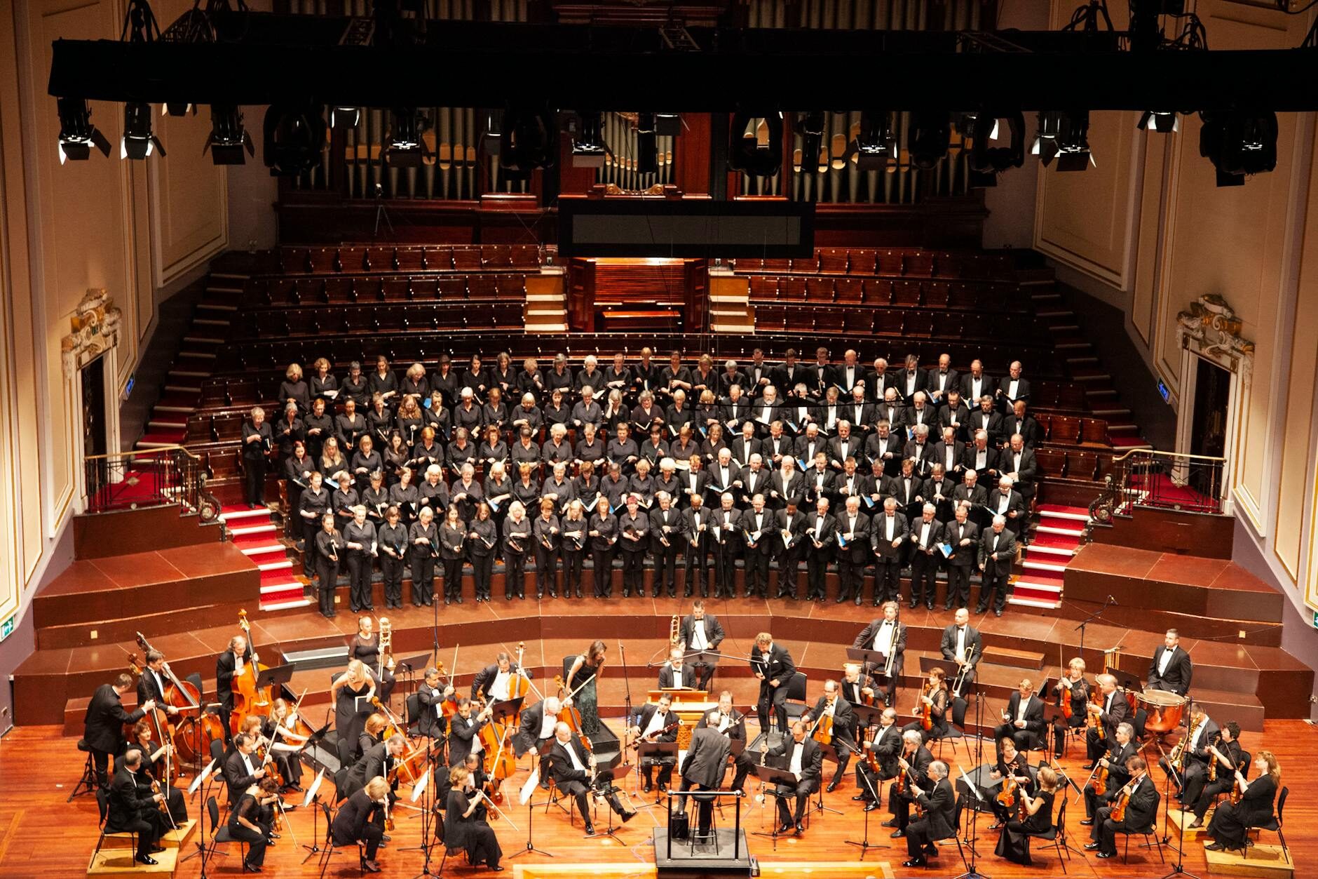 Aerial view of a full orchestra and choir performing together on stage